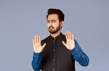 Displeased Indian guy making denial gesture on violet background