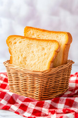 Two slices of golden-brown bread in a wicker basket on a red checkered cloth