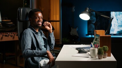 Self employed person working from home and researching different topics, examining online archived information and planning his daily tasks. Remote job setup increasing productivity. Camera B.