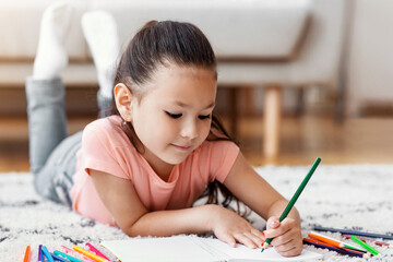 Cute Chinese Kid Sketching With Colorful Pencils Spending Weekend At Home, Lying On Floor. Little Artist Concept.