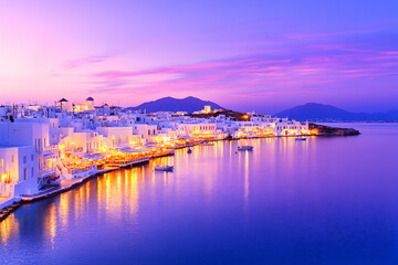 Vibrant sunset over a picturesque coastal town with illuminated buildings and calm waters