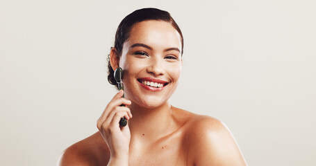 Portrait, woman and roller for skincare in studio of facial massage, blood circulation and...