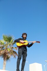 Naklejka premium Man Plays Classical Guitar On A Day Stand In The Park