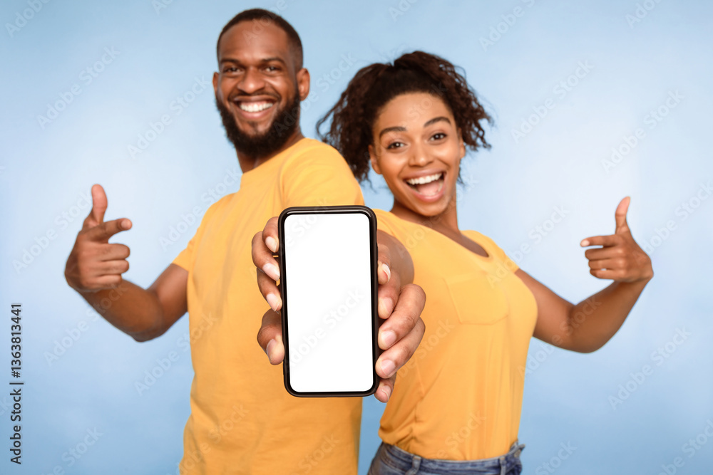 Poster use this new application. cheerful african american couple pointing at smartphone with blank screen,