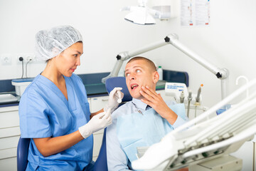 Obraz premium Male patient shows sick tooth to a dentist in a dental clinic