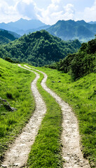 Winding dirt road through vibrant green hills and mountains under a partly cloudy sky