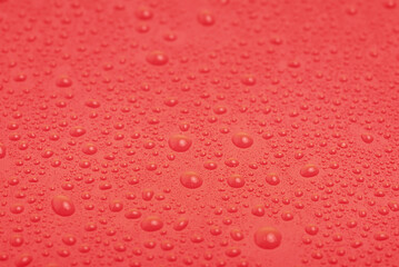 Water drops on light red plastic. Red background.