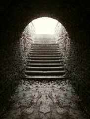 arched long tunnel with stairs. fallen autumn maple foliage. Stairway in old historical red brick...