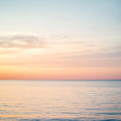 Obraz premium A romantic sunset in soft vanilla colors stretches over a calm ocean, with gentle hues blending beautifully.