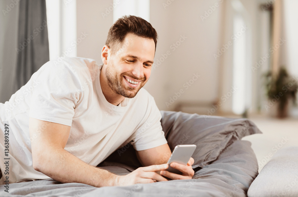 Aufkleber happy man using smartphone lying in bed at home. mobile application. copy space