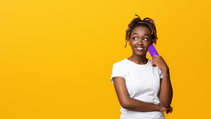 Loan for your needs. Interested black girl with credit card looking at copy space, yellow...