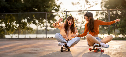 Happy young Asian girls with classmate students having fun skateboarding together in skate park, Friend happiness moment, Widescreen with copy space.