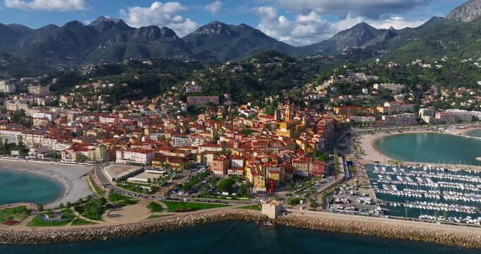 Aerial view of Menton, France. The colourful old town of Menton in summer, with historic buildings and beautiful beach at sunset. Aerial shot of historic church and colorful rooftops