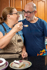 Pastry chef sharing delicious cheesecake with husband in kitchen