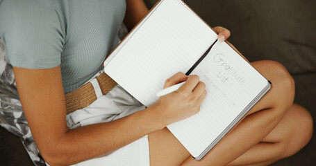 Writing, notebook and gratitude with hands of woman on sofa for inspiration, self care journal and reflection. Reminder checklist, mental health prompt and relax with person in living room of home