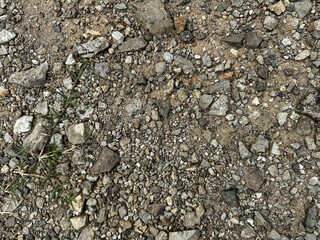Textured Ground Featuring Gravel and Soil with Small Green Grass Patches in Natural Environment