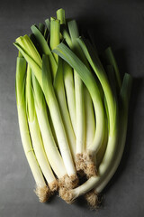 Fresh green leeks on grey table, top view
