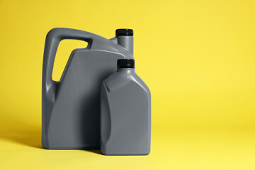 Two grey plastic canisters on yellow background, space for text