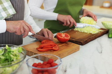 Senior couple cooking together at table in kitchen, closeup