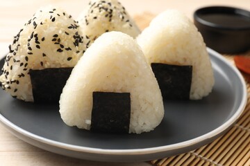 Rice balls (onigiri) and soy sauce on table, closeup. Traditional Japanese dish
