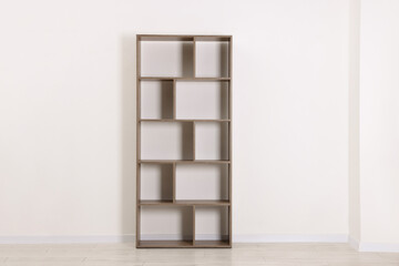 Empty wooden shelving unit near white wall indoors