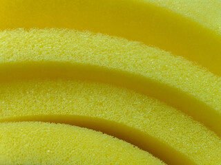 thin sheet of yellow sponge foam. curved fold detail. polyurethane foam texture.
