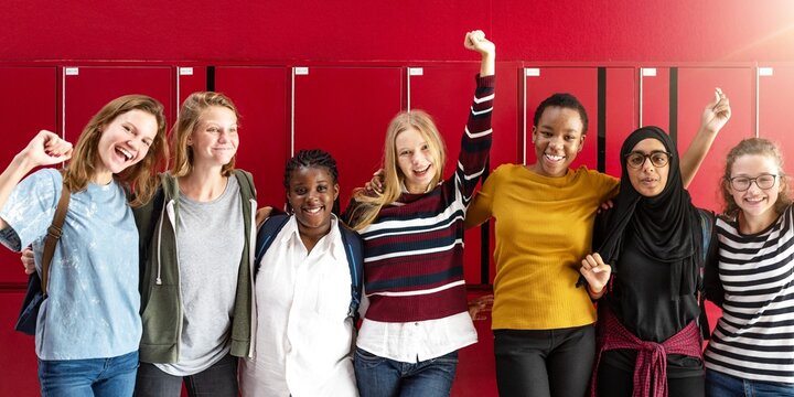 Diverse teenage girls in school. Young girls cheering and celenbrating. Happy international teenage students at school. Girls with arms up, celebrating a win at school. International high school.