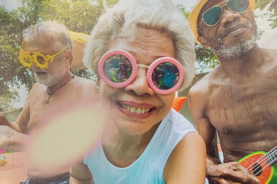 Closeup of diverse senior adults sitting by the pool enjoying summer together