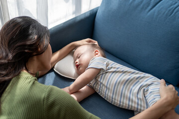 A single Asian mother lovingly cares for and raises her baby boy at home. 