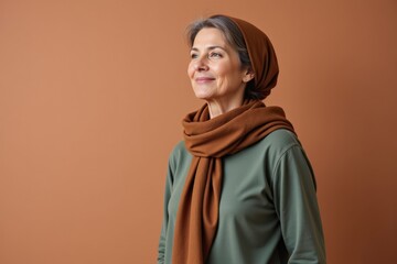 Portrait of a Middle-Aged Caucasian Woman with Grey Hair Wearing a Brown Scarf and Sweater Against a Warm Brown Background
