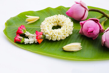 Jasmine garland with white jasmine flowers and red roses at the ends. Additionally, there are pink lotus buds and white champaka flowers
