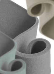 three thin colored foam sponges rolled in a spiral style on a white background