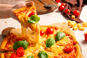 Woman taking slice of tasty pizza margarita on white table