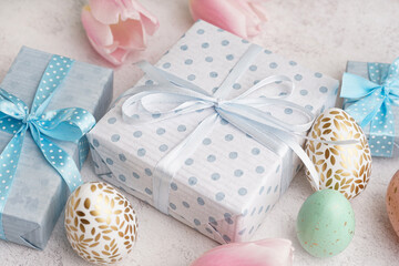 Painted Easter eggs with gift boxes and tulip flowers on white grunge background