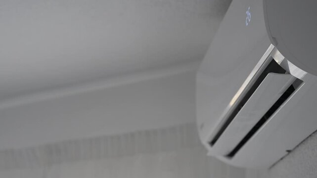 split of a domestic air conditioning unit in operation, moving its blades to distribute the air throughout the room