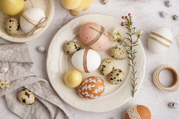 Plates with festive decorated Easter eggs and spring flowers on white background