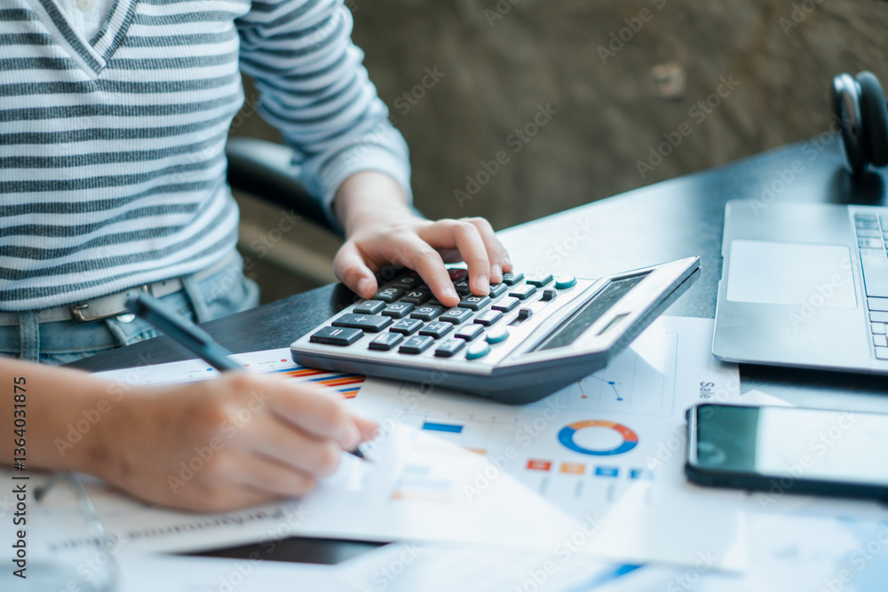 Poster a business professional using a calculator and reviewing financial charts at a desk, focusing on dat