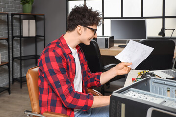 Male technician with manual repairing computer in service center