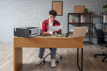 Male technician with manual repairing computer in service center