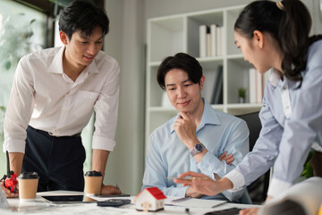 Design Presentation and Collaboration. A professional team discussing a model house design with blueprints on the table.