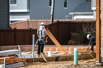 Construction worker, carpenter, in tool belt and hard hat on housing development project,...