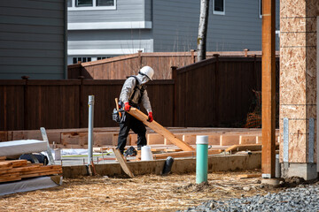 Construction worker, carpenter, in tool belt and hard hat on housing development project,...