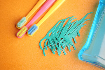 Oral hygiene tools displayed on vibrant orange background