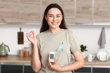 Diabetic young woman with blue awareness ribbon and glucometer in kitchen