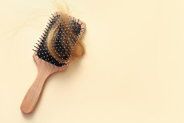 Brush with hair strand on beige background. Hair loss problem