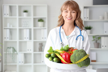 Female nutritionist with healthy vegetables and tape measure in office