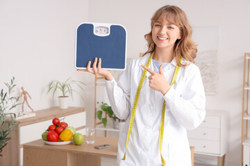Female nutritionist pointing at weight scales in office