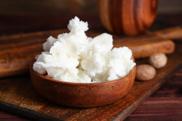Bowl with shea butter on wooden board, closeup