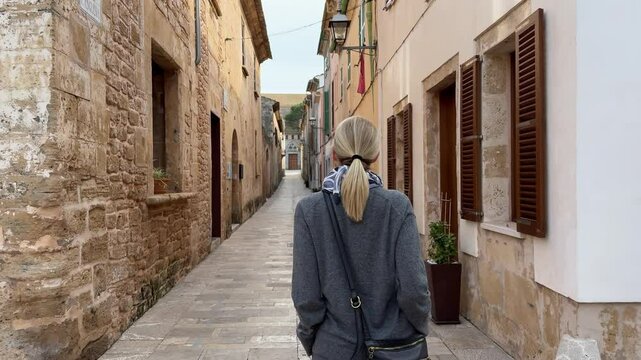 Woman walking through charming streets of Alcudia Spain
