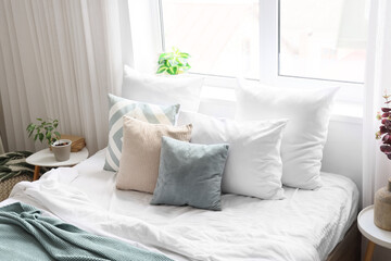 Big bed with soft pillows in light bedroom